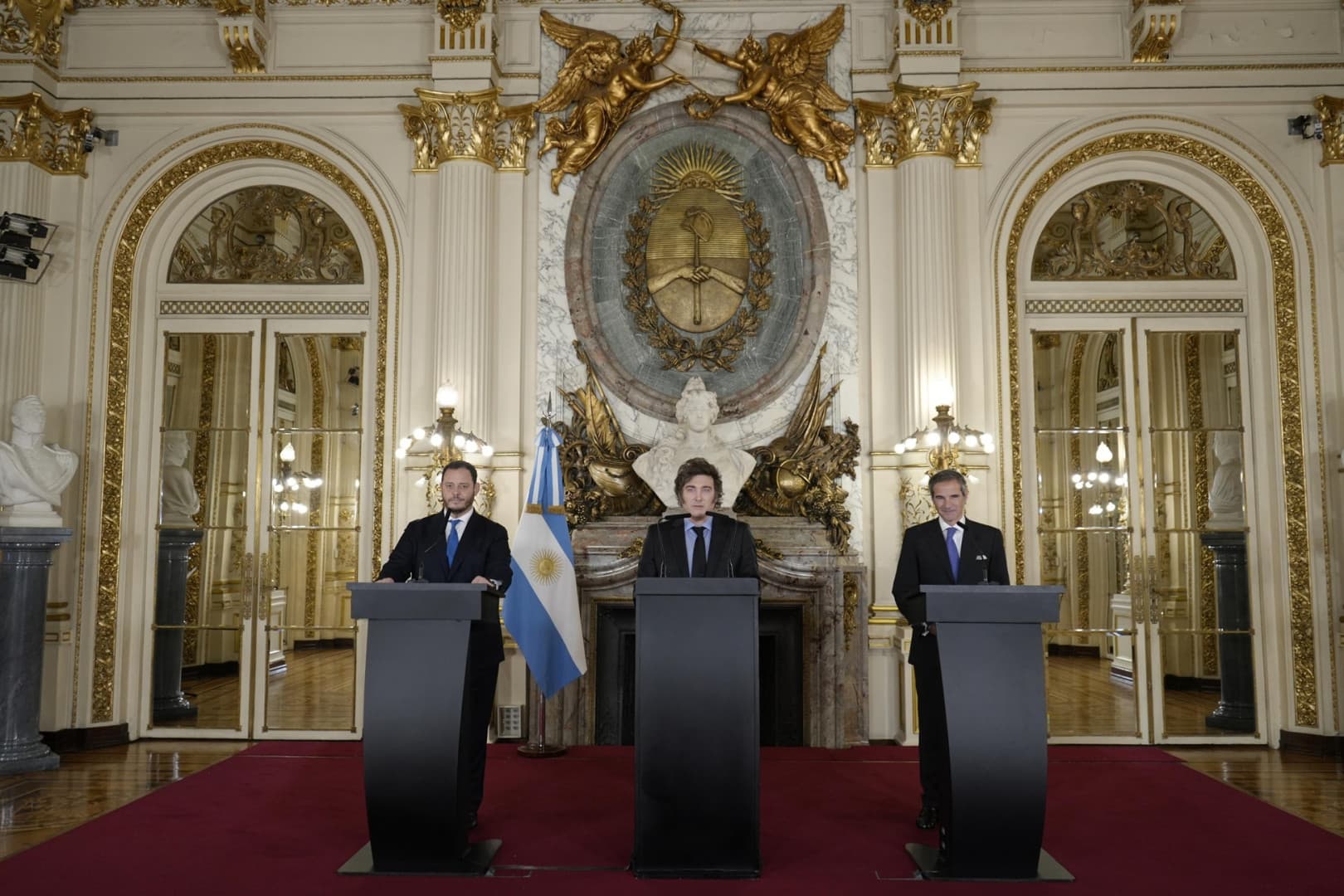 Demian Reidel, Javier Milei, and Rafael Mariano Grossi at three lecterns in the Casa Rosada